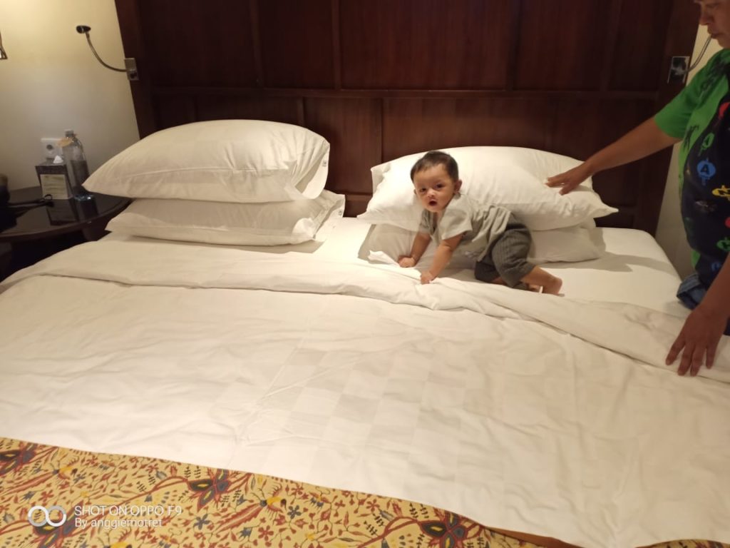 bayi yang bermain di kasur kamar hotel yang nyaman 